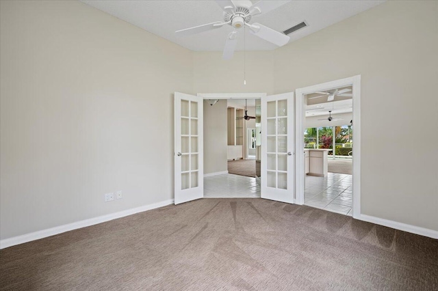 carpeted spare room with tile patterned floors, french doors, a ceiling fan, baseboards, and visible vents