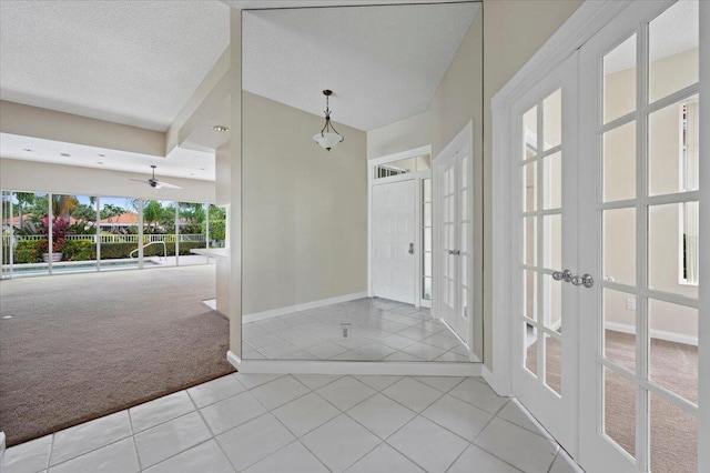 carpeted entryway with french doors, a ceiling fan, baseboards, and tile patterned flooring