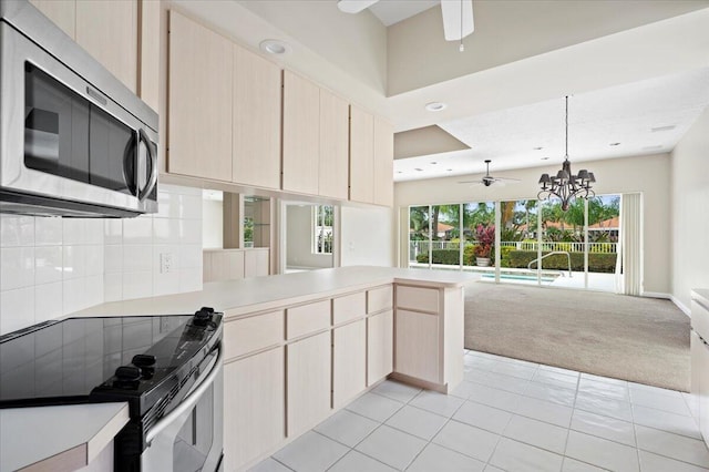 kitchen with stainless steel appliances, open floor plan, ceiling fan with notable chandelier, and a peninsula
