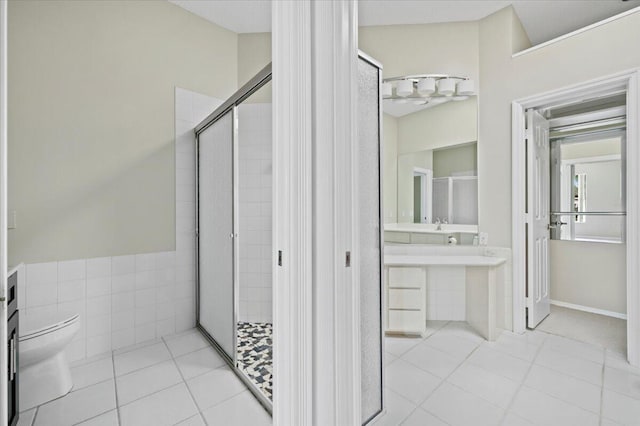 bathroom with a shower with door, tile patterned floors, vanity, and toilet