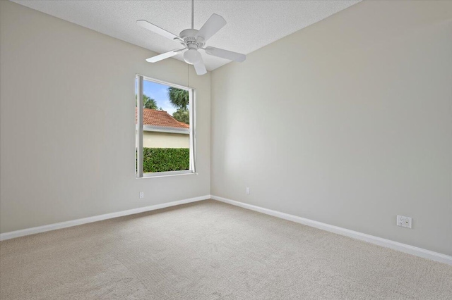 carpeted spare room with a textured ceiling, ceiling fan, and baseboards