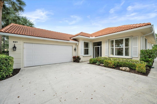 view of front of house with an attached garage, a tile roof, and concrete driveway