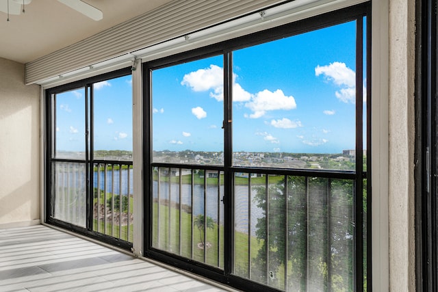 unfurnished sunroom featuring a water view and ceiling fan