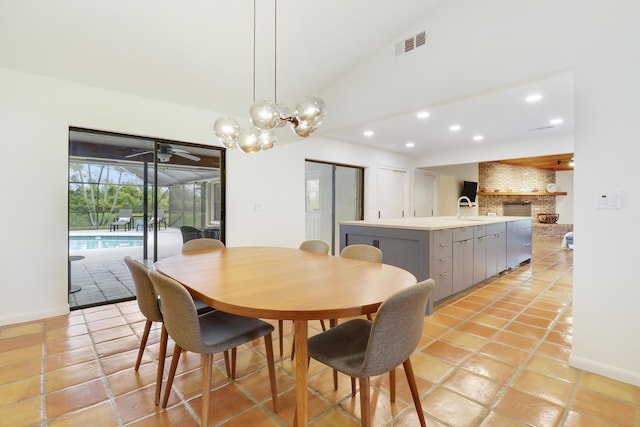 dining area featuring sink, a brick fireplace, vaulted ceiling, and light tile patterned flooring