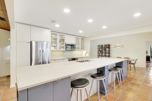 kitchen with sink, stainless steel appliances, white cabinetry, and a kitchen bar