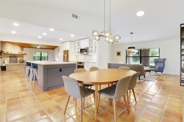 tiled dining space featuring sink and a brick fireplace