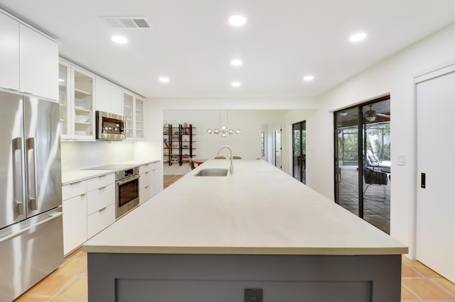 kitchen featuring appliances with stainless steel finishes, white cabinetry, and a center island with sink