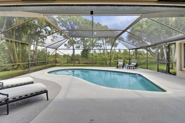 view of pool with a patio area and glass enclosure