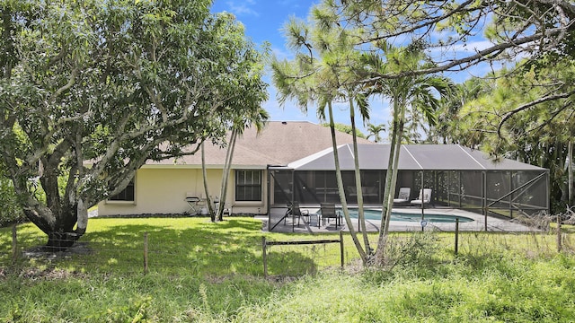 rear view of house featuring a lawn, a patio area, and glass enclosure