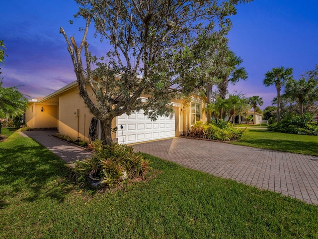 view of property hidden behind natural elements featuring a garage and a yard