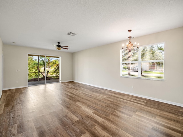 empty room with ceiling fan with notable chandelier, wood-type flooring, and a textured ceiling