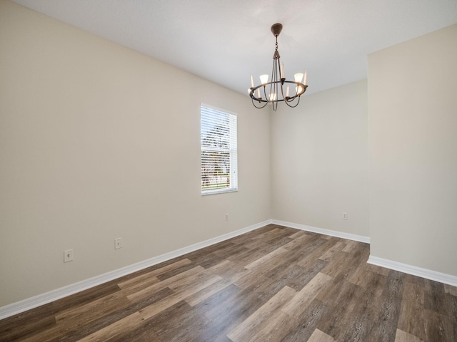 spare room with dark hardwood / wood-style flooring and a chandelier