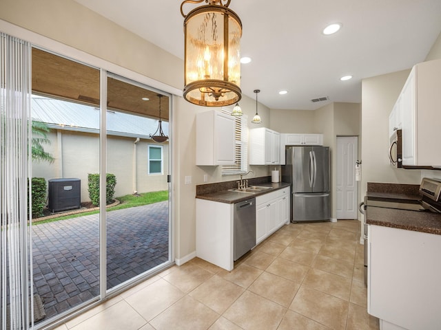 kitchen featuring stainless steel appliances, sink, light tile patterned floors, decorative light fixtures, and white cabinets