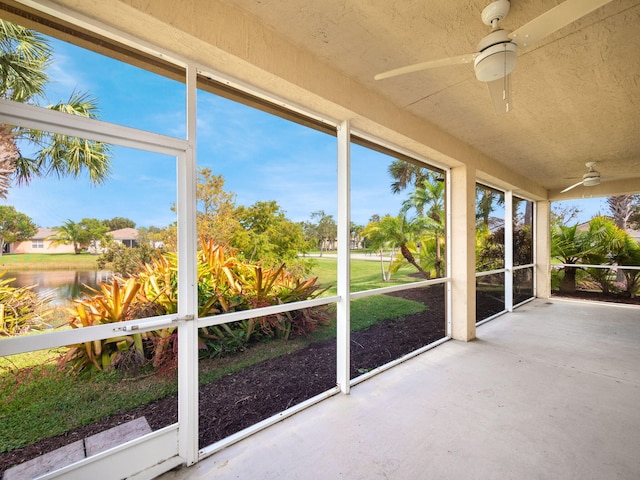 unfurnished sunroom with a water view and ceiling fan