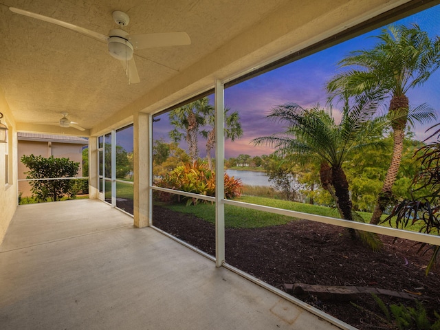 unfurnished sunroom with a water view and ceiling fan