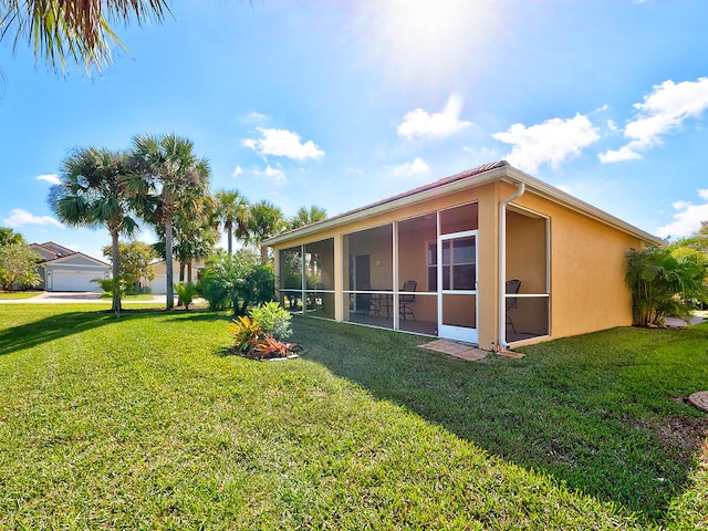 view of property exterior with a garage, a sunroom, and a yard