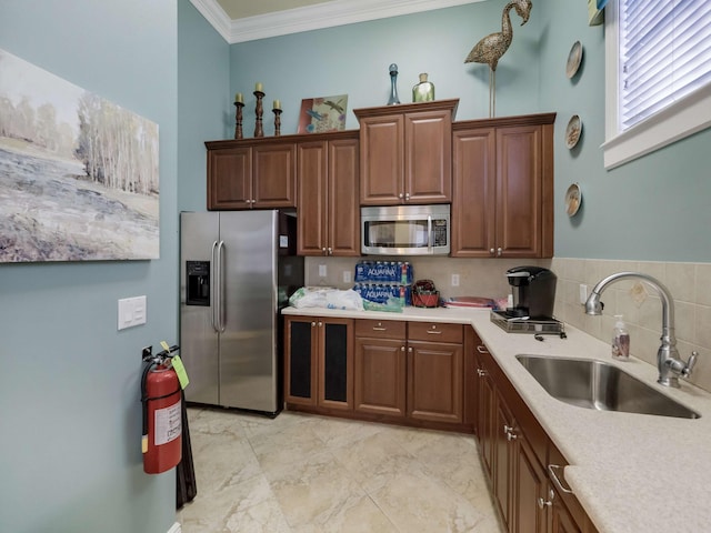 kitchen featuring tasteful backsplash, sink, ornamental molding, and stainless steel appliances