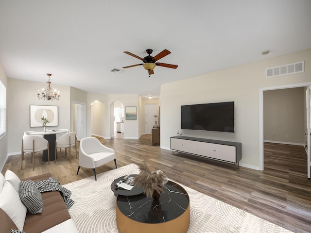 living room with dark hardwood / wood-style floors and ceiling fan with notable chandelier