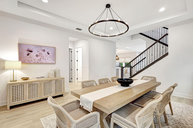 dining space with light hardwood / wood-style floors and an inviting chandelier