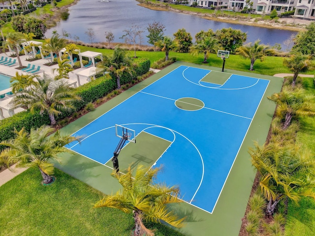 view of sport court with a water view and a yard