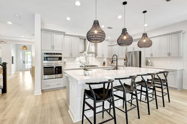 kitchen featuring a kitchen bar, appliances with stainless steel finishes, light wood-type flooring, a spacious island, and sink