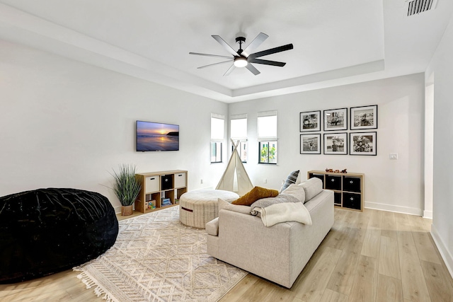 living room featuring a raised ceiling, ceiling fan, and hardwood / wood-style floors