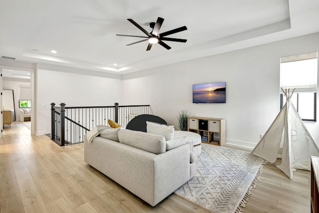 living room featuring a tray ceiling, a wealth of natural light, and light hardwood / wood-style floors