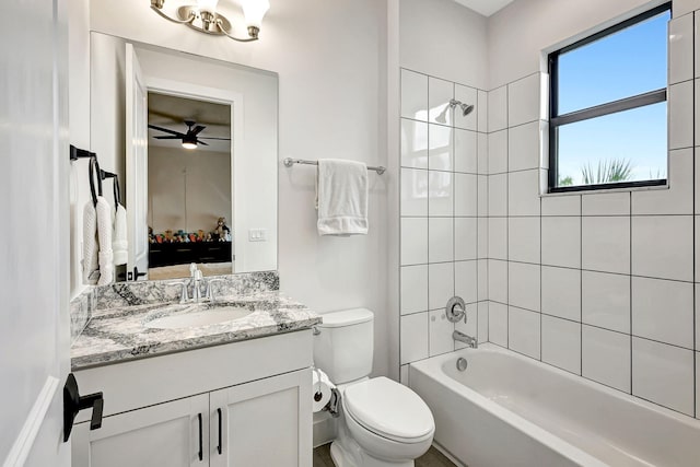 full bathroom featuring ceiling fan, vanity, tiled shower / bath combo, and toilet