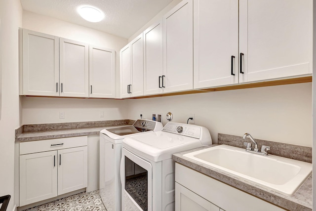 laundry area with cabinets, a textured ceiling, washing machine and dryer, and sink