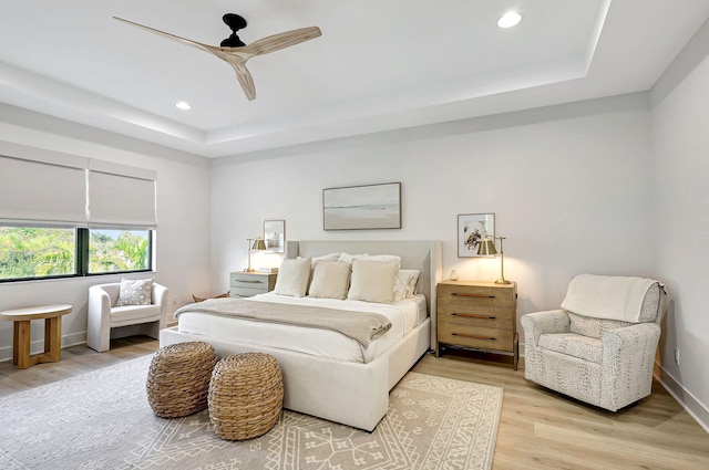 bedroom featuring hardwood / wood-style flooring, ceiling fan, and a raised ceiling