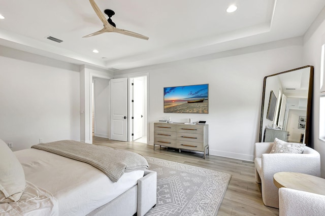 bedroom featuring a tray ceiling, ceiling fan, and light wood-type flooring