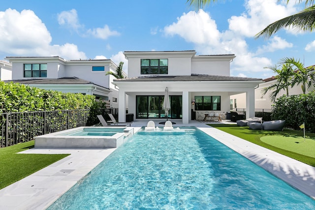 rear view of house featuring a pool with hot tub and a patio