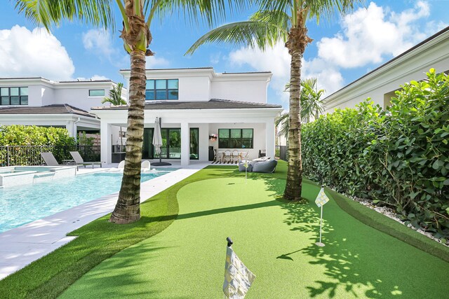 rear view of house featuring a swimming pool with hot tub and a patio