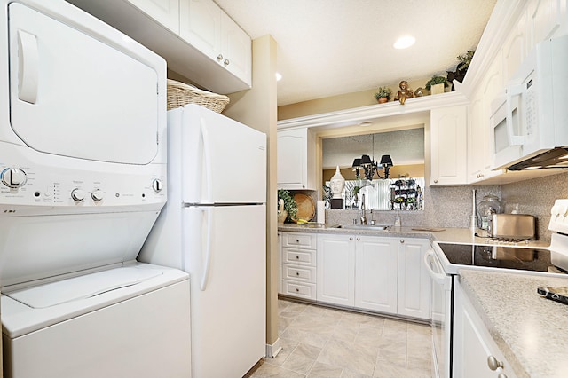 interior space with white cabinetry, stacked washer / dryer, sink, and white appliances