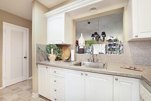 kitchen featuring backsplash, sink, a notable chandelier, white cabinets, and a textured ceiling