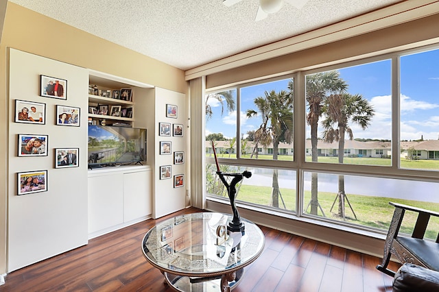 living area with ceiling fan, a textured ceiling, and dark hardwood / wood-style flooring