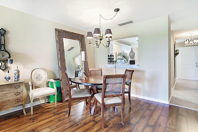 dining room featuring a notable chandelier, a textured ceiling, and dark hardwood / wood-style flooring