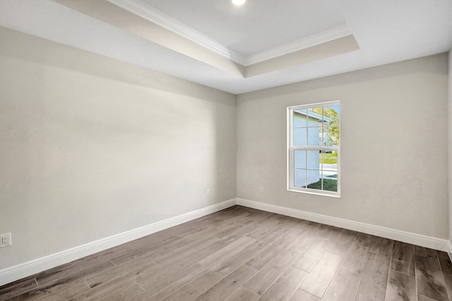 empty room featuring crown molding, hardwood / wood-style floors, and a tray ceiling