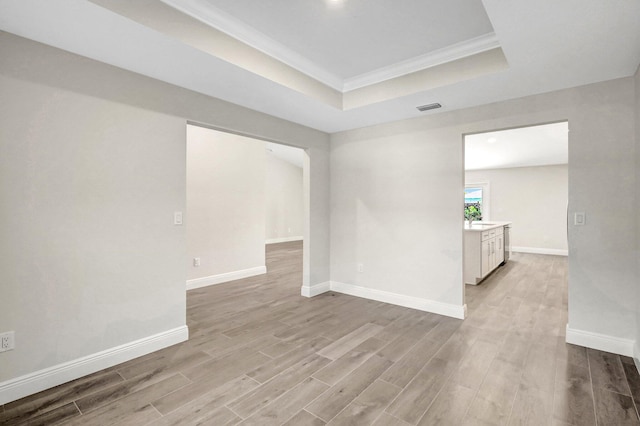 spare room with crown molding, light hardwood / wood-style flooring, and a raised ceiling