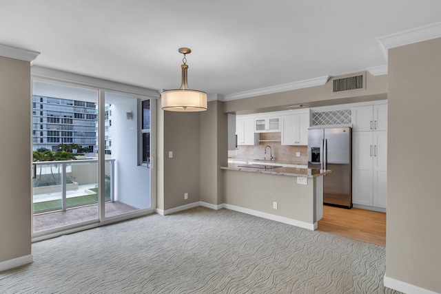 kitchen featuring stainless steel refrigerator with ice dispenser, kitchen peninsula, crown molding, pendant lighting, and white cabinets