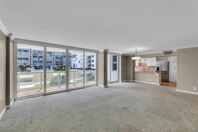 unfurnished living room with crown molding, sink, and light colored carpet