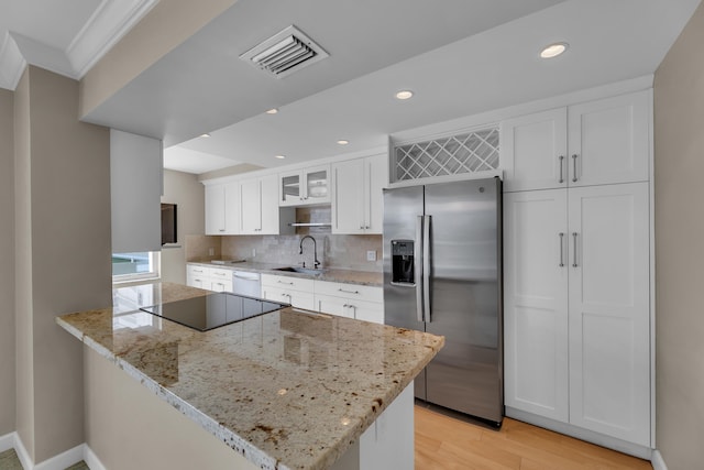 kitchen featuring stainless steel fridge, white cabinetry, light wood-type flooring, sink, and light stone counters