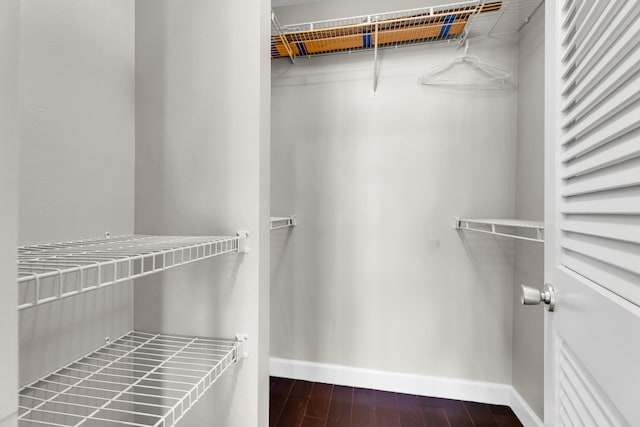 walk in closet with dark wood-type flooring