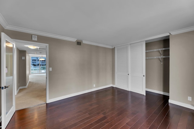 unfurnished bedroom featuring dark wood-type flooring, a closet, and ornamental molding