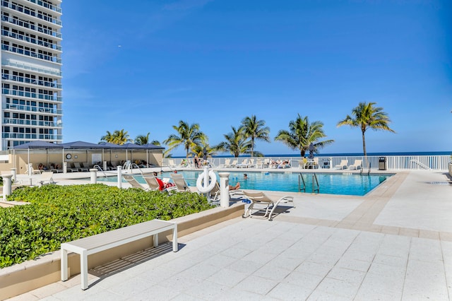 view of pool featuring a water view and a patio