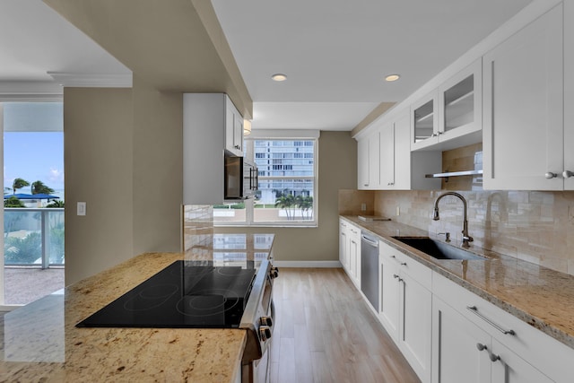 kitchen featuring sink, light wood-type flooring, white cabinetry, stainless steel appliances, and light stone counters