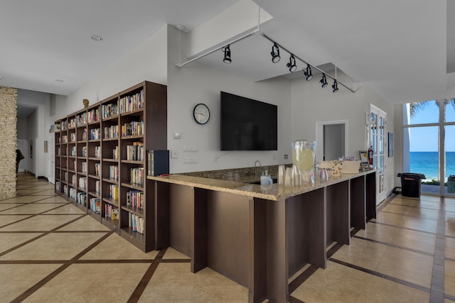 interior space with kitchen peninsula, stone counters, and rail lighting