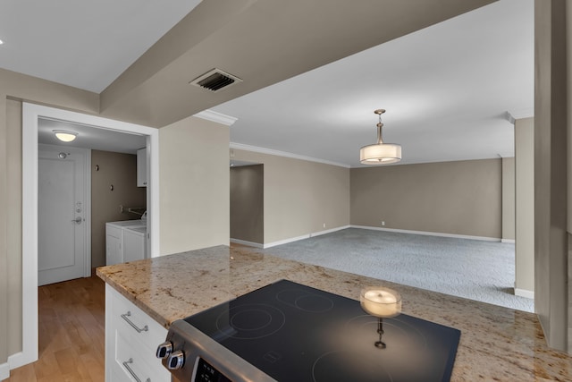 kitchen with white cabinetry, stove, washing machine and clothes dryer, pendant lighting, and light hardwood / wood-style floors