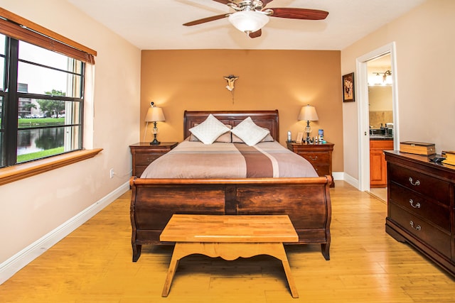 bedroom featuring connected bathroom, light wood-type flooring, and ceiling fan