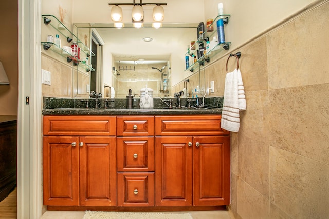 bathroom featuring vanity, a shower, and tile walls